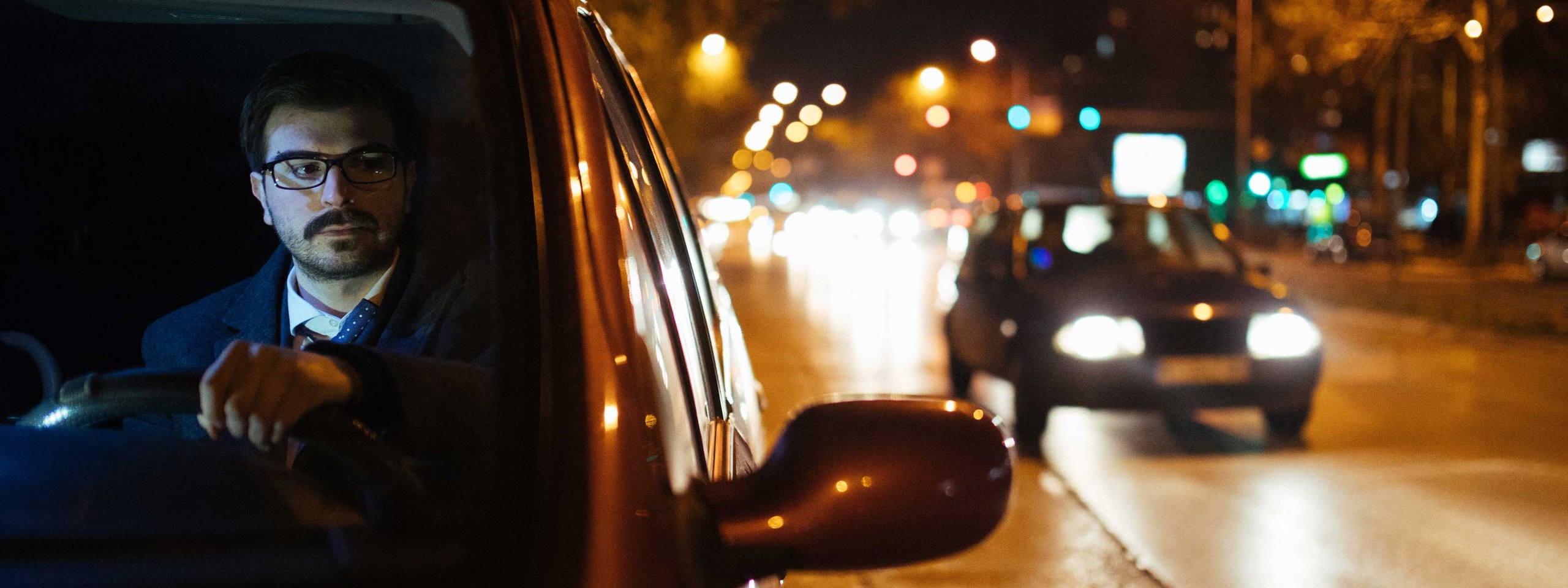 Mann sitzt im Auto und beobachtet den Verkehr