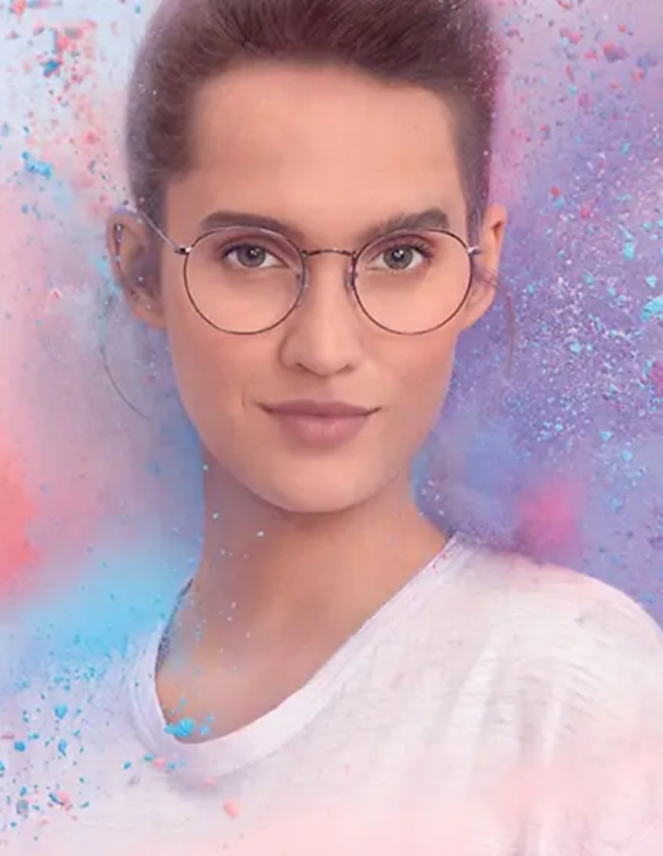 Frau mit Brille vor gemalten Hintergrund mit Farbklecksen. 